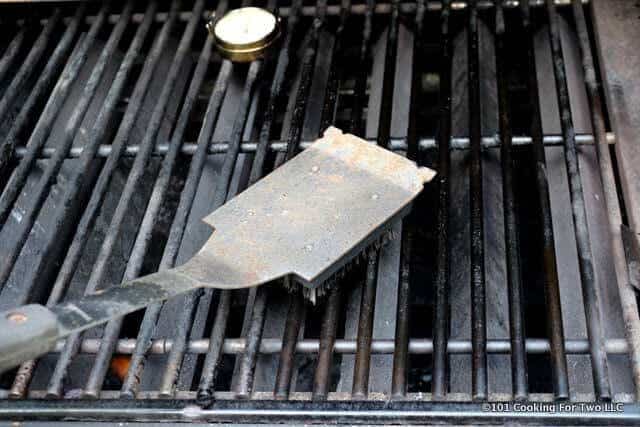 Picture of brush cleaning the grill grates with a surface thermometer in place