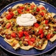 Chile Nachos on a blue plate topped with sour cream