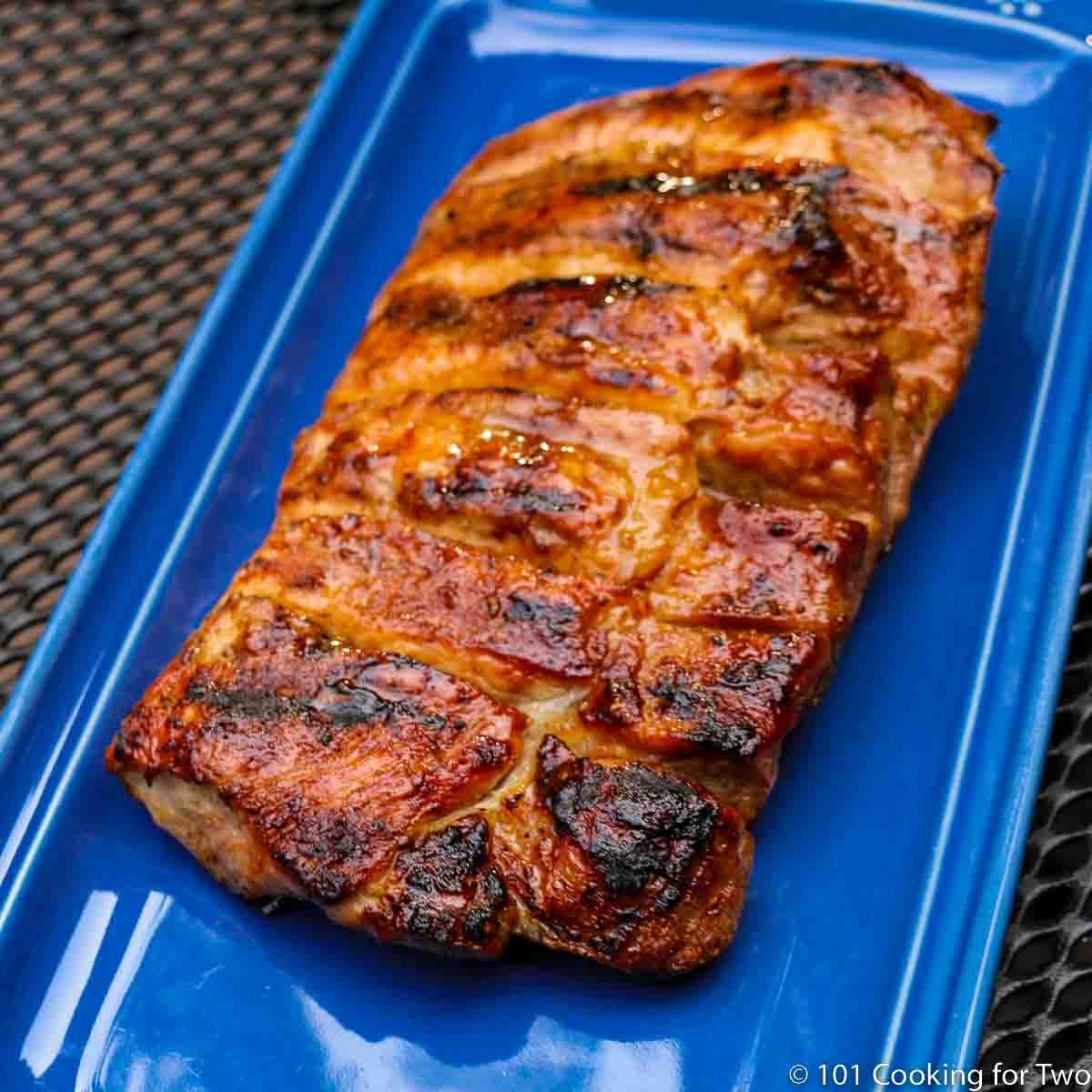 A done boneless pork rib slab on a blue plate.