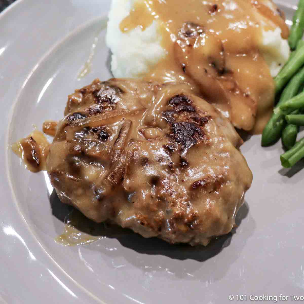 closeup image of Salisbury Steak on a blue plate with potatoes and gravy