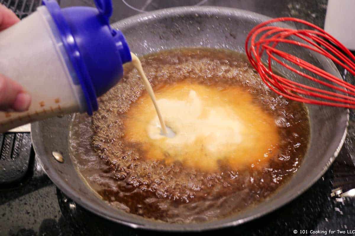 adding flour to borth in skillet with whisk