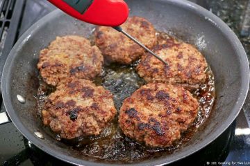 cooked patties in black skillet with thermometer