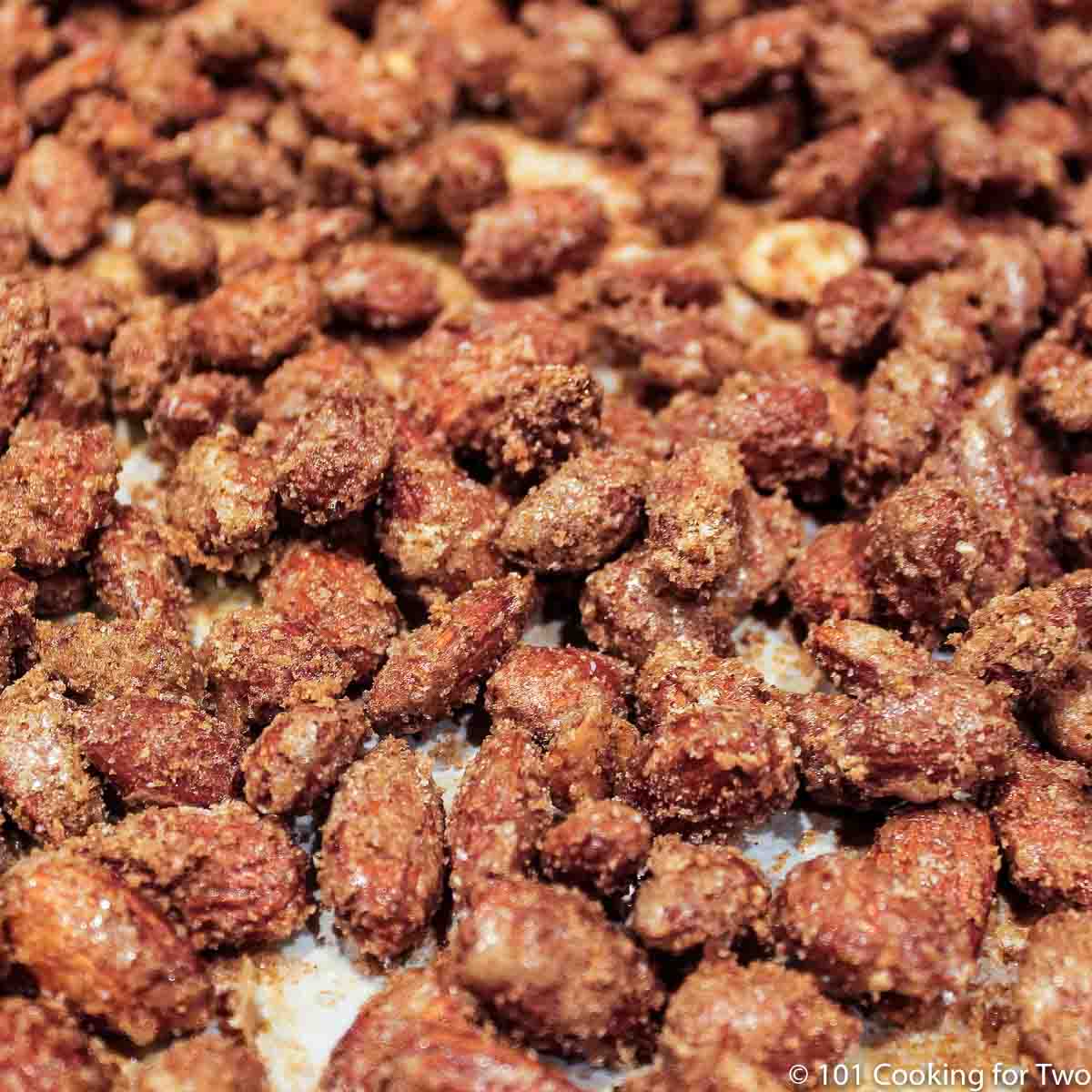 close up image finished candied nuts on the cooking tray with white parechment paper