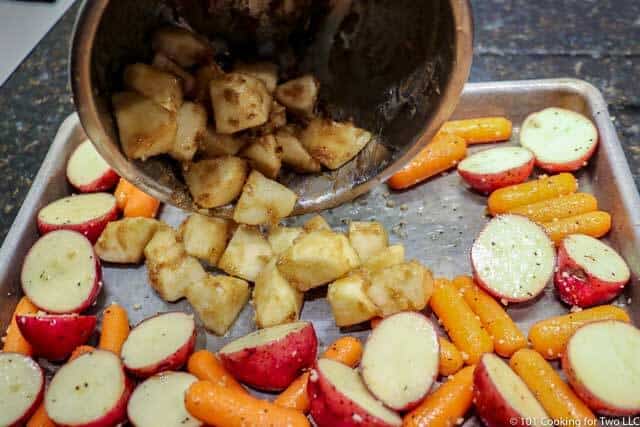 image of the sheet pan with the potatoes and carrots around the edge and the apple being added in the center
