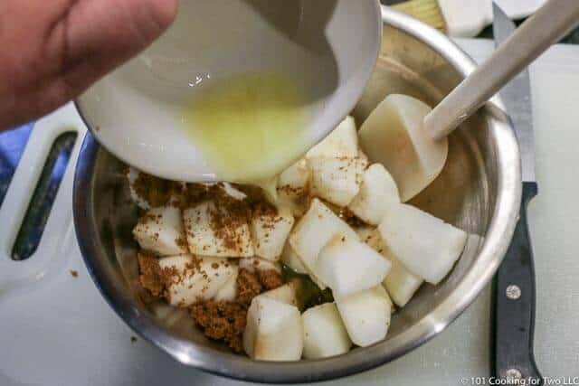 image of melted butter being added to the apple in a metal bowl