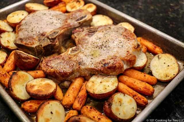 image of the pan with pork chops and veggies nicely done coming out of the oven
