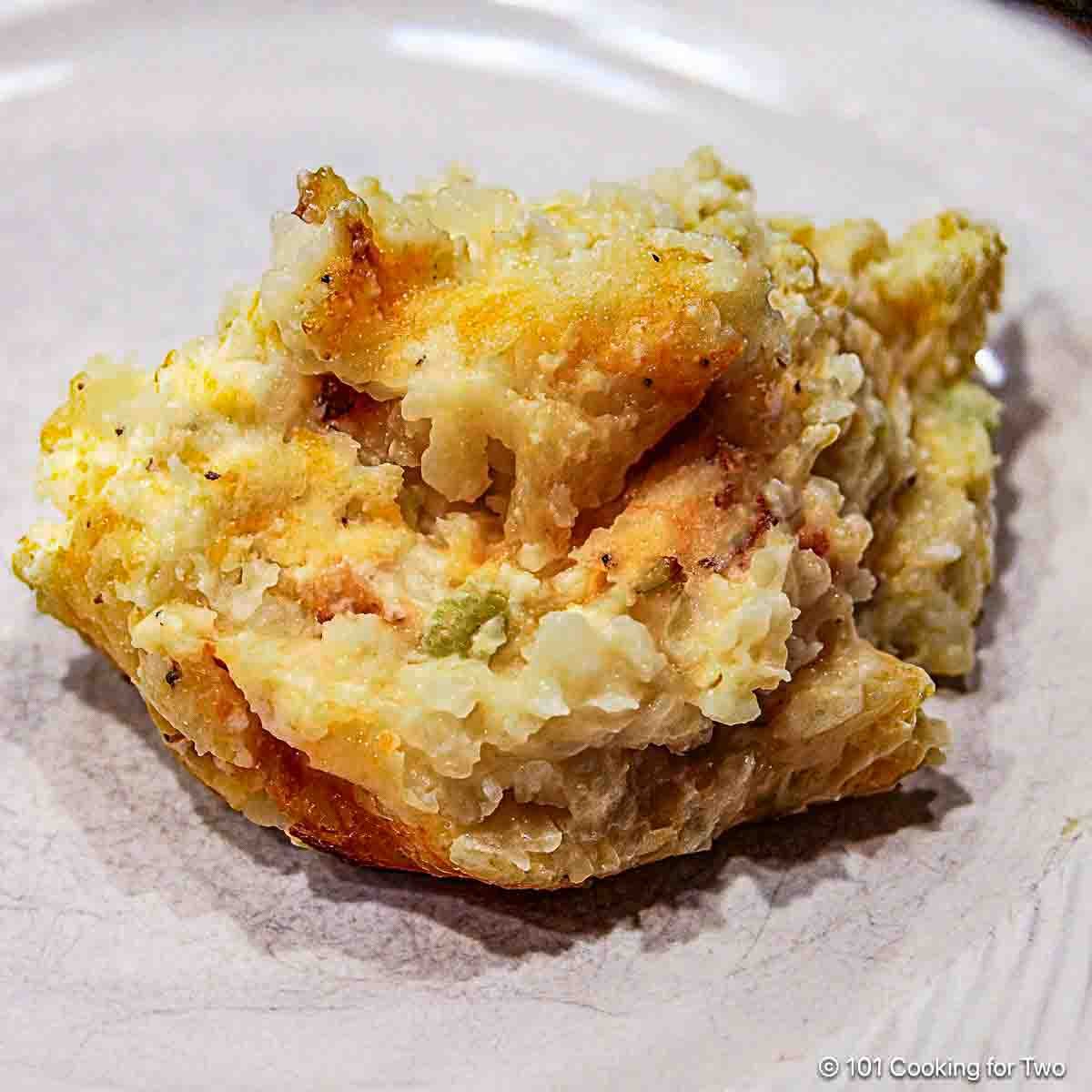 cheesy potato casserole on a white plate.