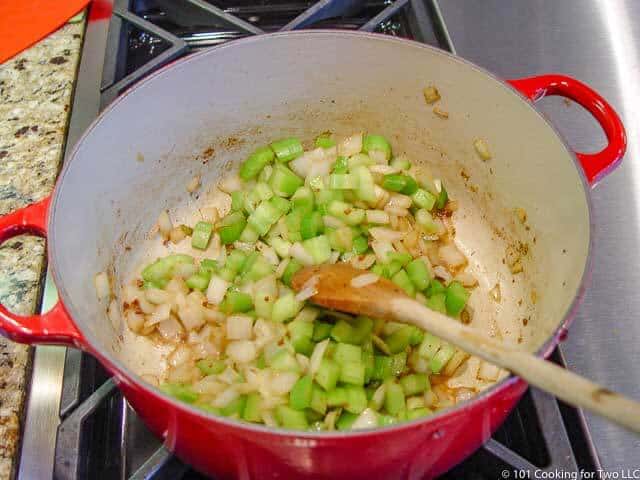 image of cooking celery and onion in a red Dutch oven