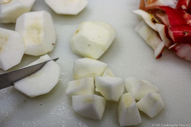 image of a slice of apple being cut on a white cutting board