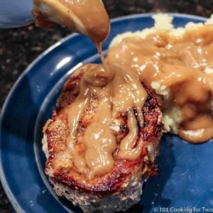 thick pork chops with gravy on a blue plate