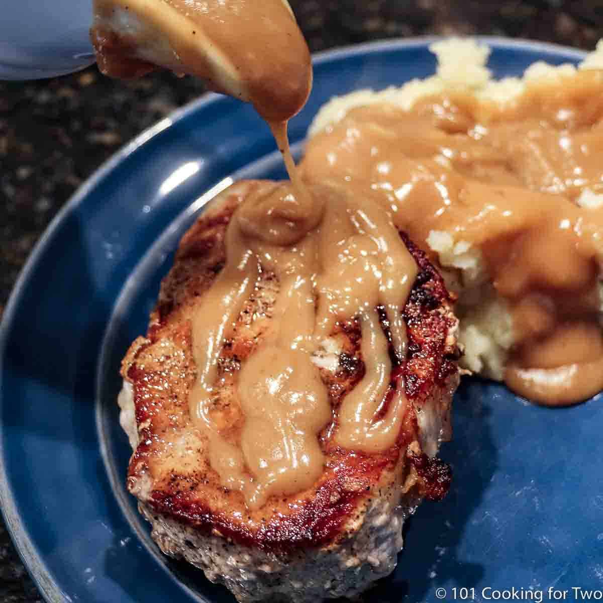 thick pork chop with gravy on a blue plate