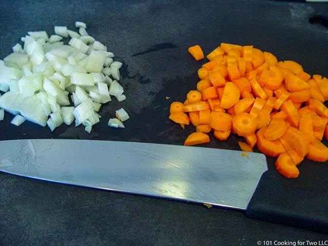 image of chopped carrot and onion on a black chopping board