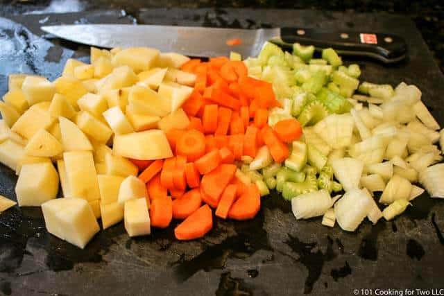 image of chopped potatoes, carrots and onion on a black chopping board