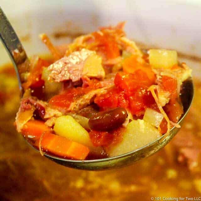 large ladle of ham and vegetable soup over the crock pot