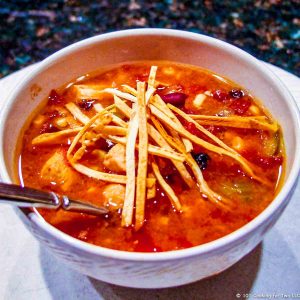 White bowl with tortilla soup topped with strips