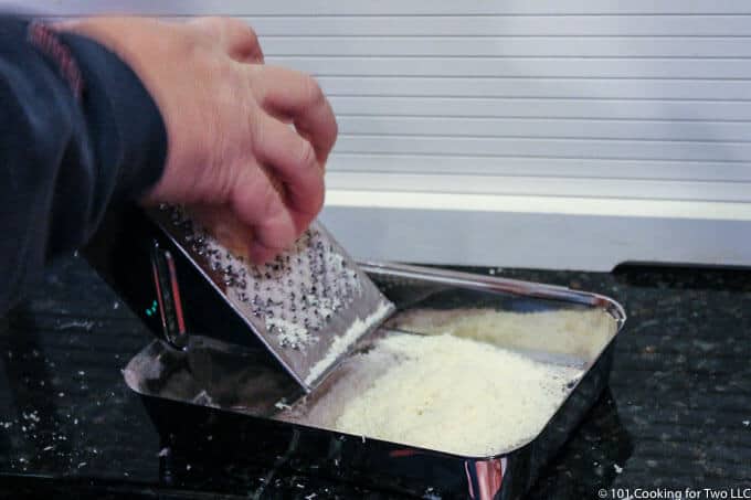 grating Parmesan cheese into a chrome pan