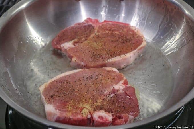 pork chops in pan with shimmering oil