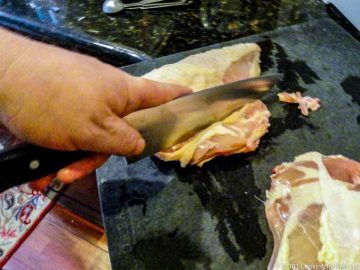 image of cutting off ribs from the split chicken breast with a large knife