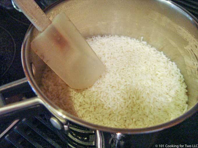 rice in a pan of broth on the stovetop
