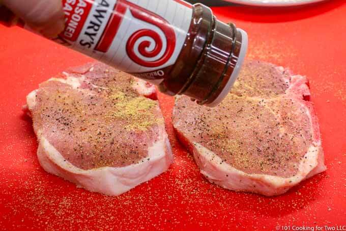 seasoning with the pork chops on a red mat