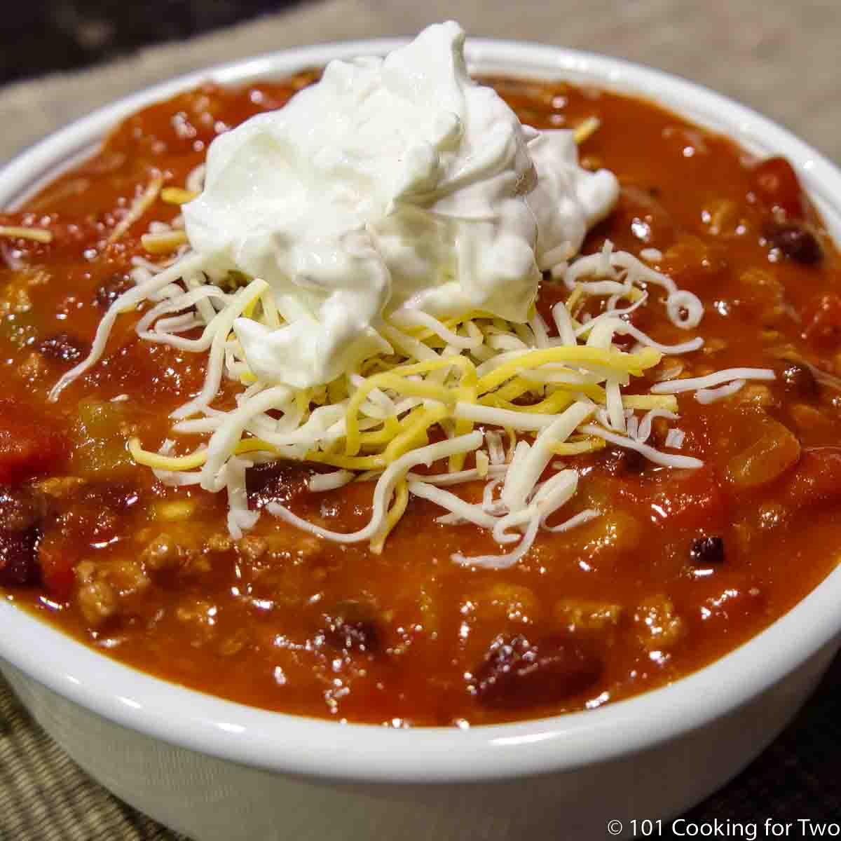 Taco Soup in white bowl with sour cream and cheese.