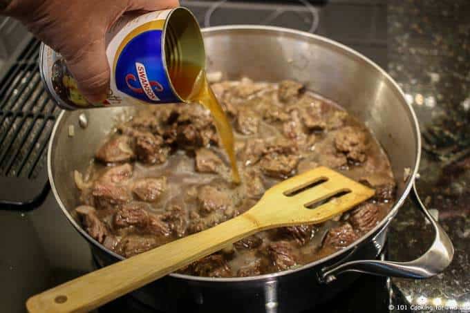 image of adding beef broth from a can to cooked beef in fry pan
