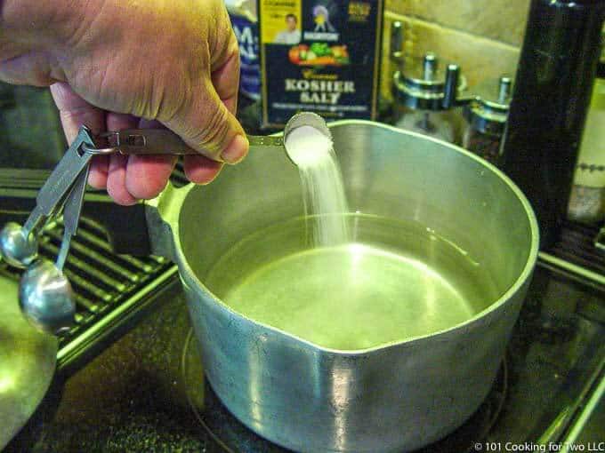 adding salt to water on stovetop