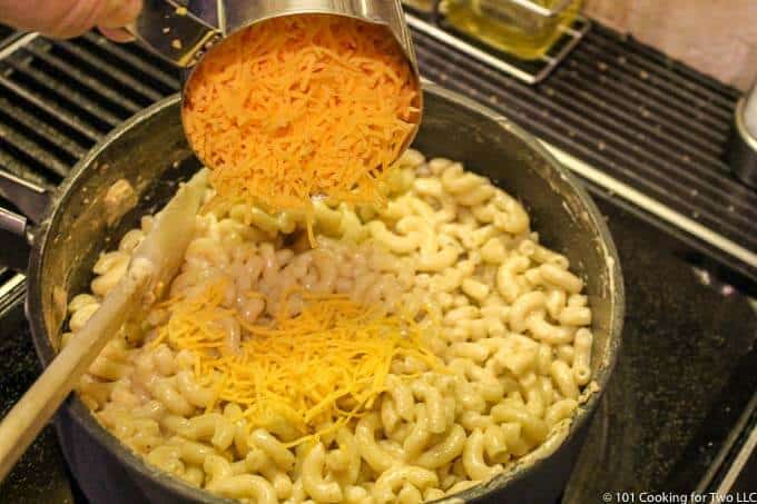 adding the cheese to the cooked macaroni