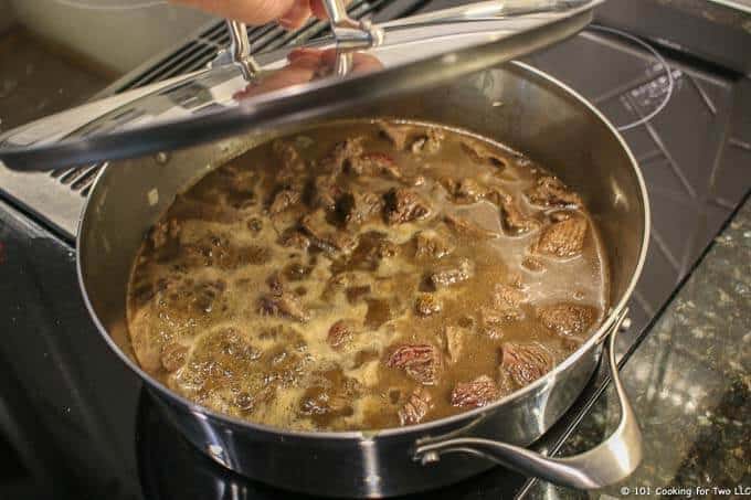 image of the pan with boiling meat and broth being covered with a pan