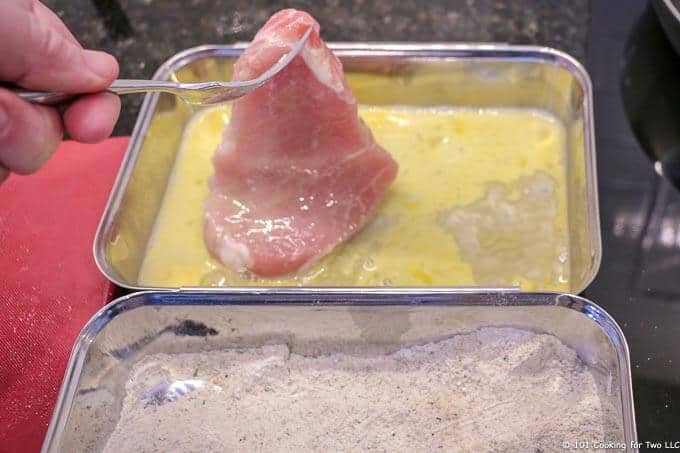 image of pork chop coming out of egg wash