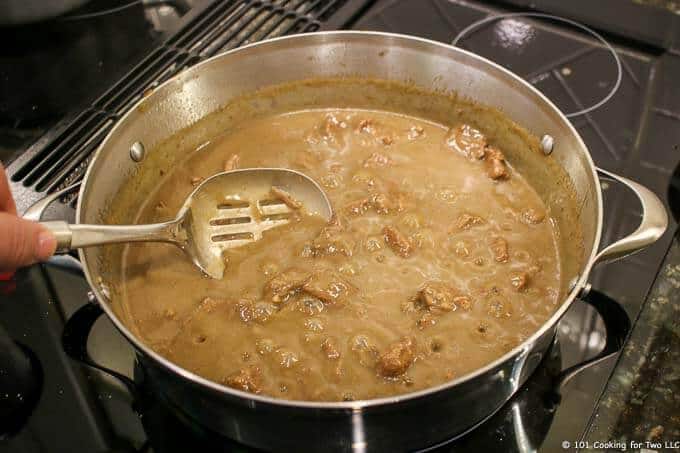 image of stirring gravy on stovetop with slotted spoon