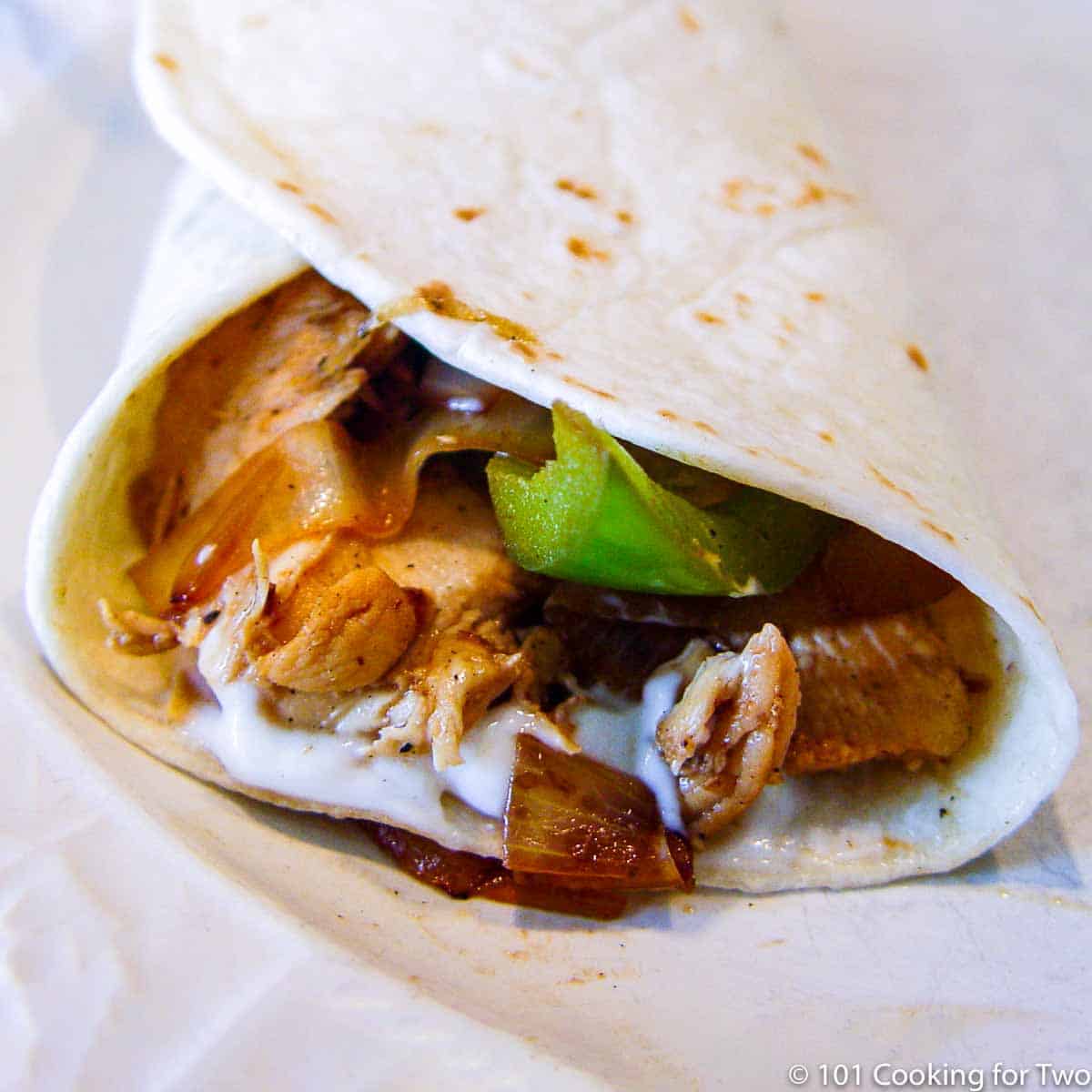 Close up image of a chicken fajita on a white plate