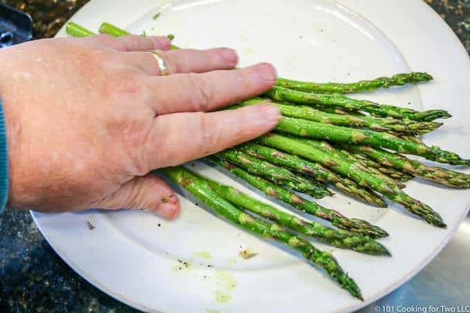 coating asparagus with oil and seasoning