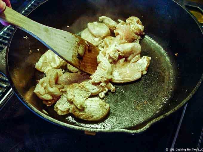 image of cooking strips of chicken in black cast iron pan