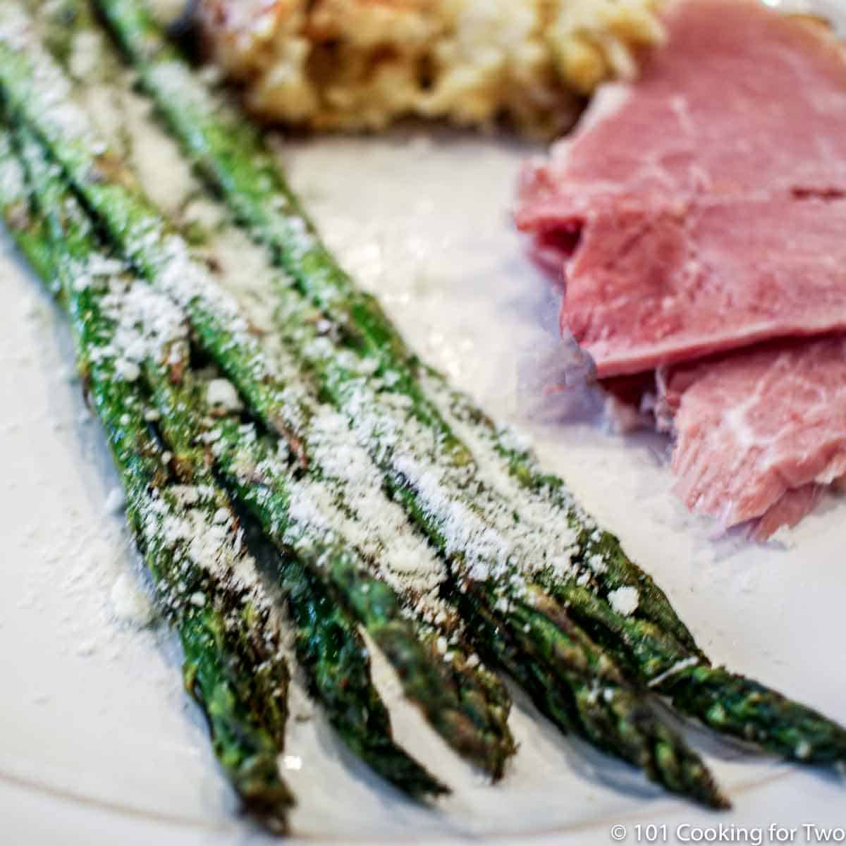 asparagus on a white plate with Parmesan.