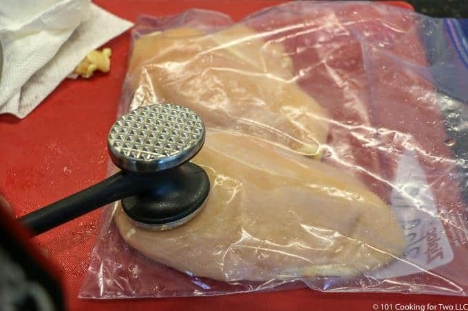 using a meat mallet to even out the chicken