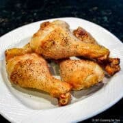 Baked chicken legs on a white plate.