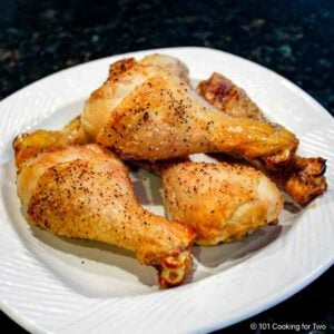 Baked chicken legs on a white plate.