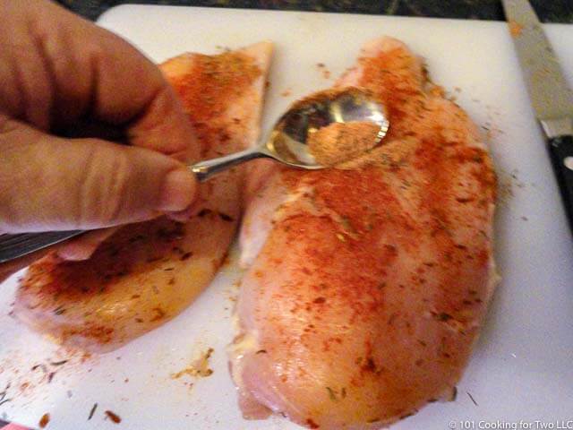 applying seasoning to chicken breasts