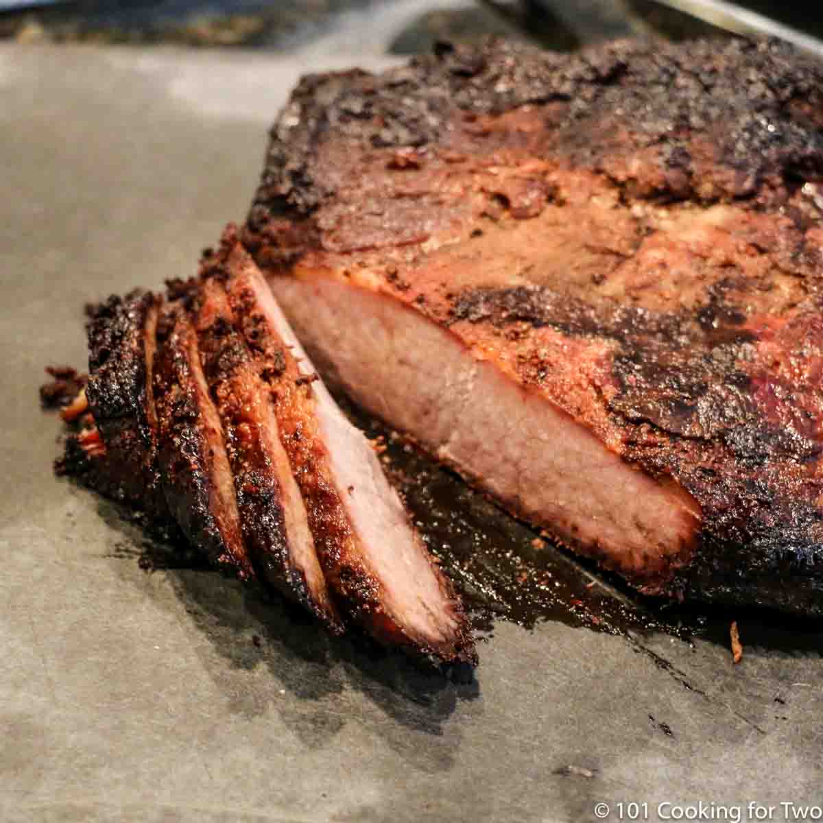 Cooked brisket on a gray board.