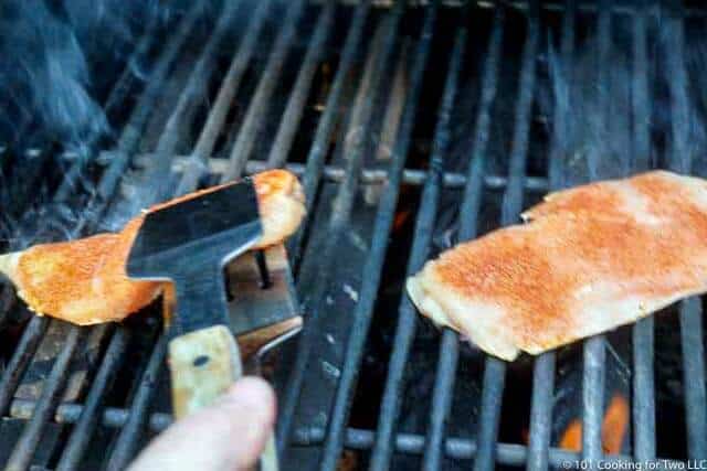 placing the seasoned chicken breast on the grill