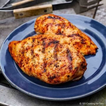 Two grilled chicken breasts on a blue plate.