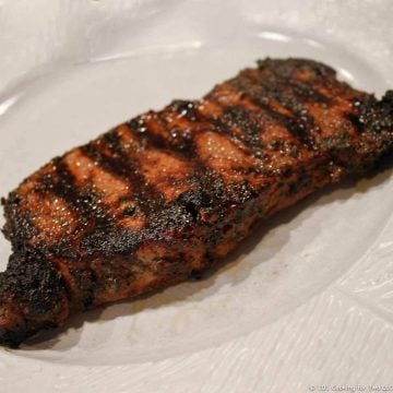 marinaded strip steak on a white plate.