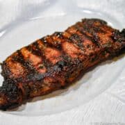 grilled marinaded strip steak ona white plate