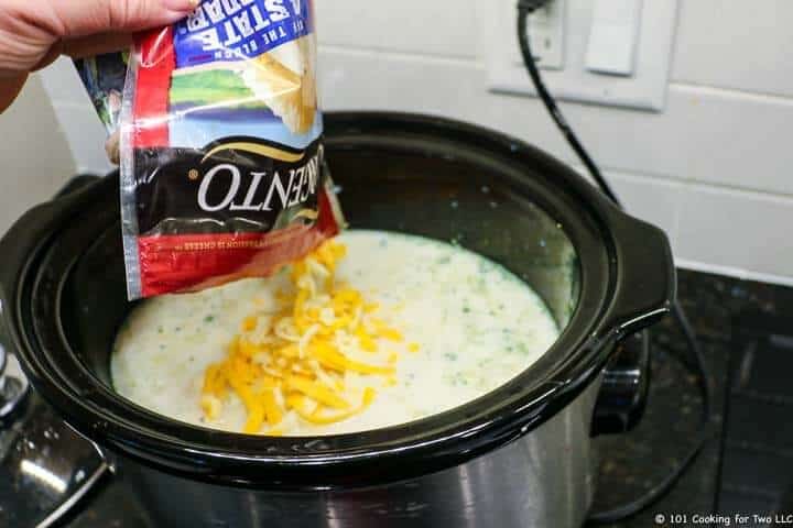 adding cheese to crock pot.