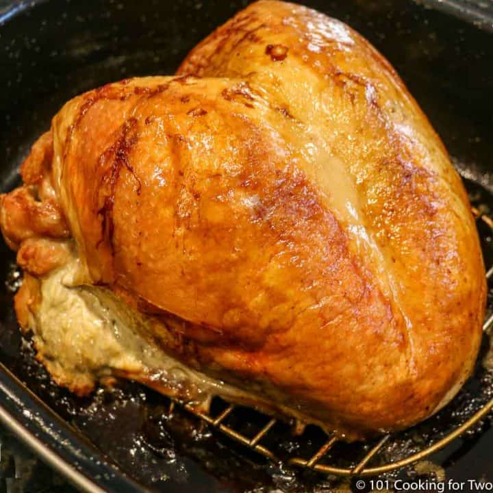 A cooked turkey breast in a roasting pan.