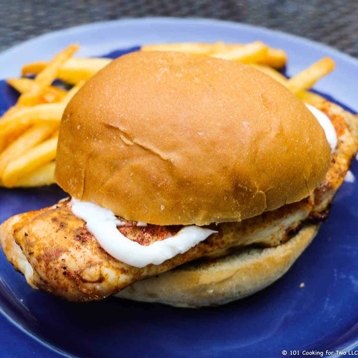 grilled chicken sandwich on blue plate.