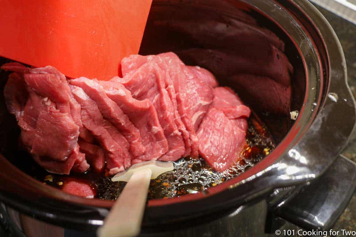 adding sliced beef to crock pot