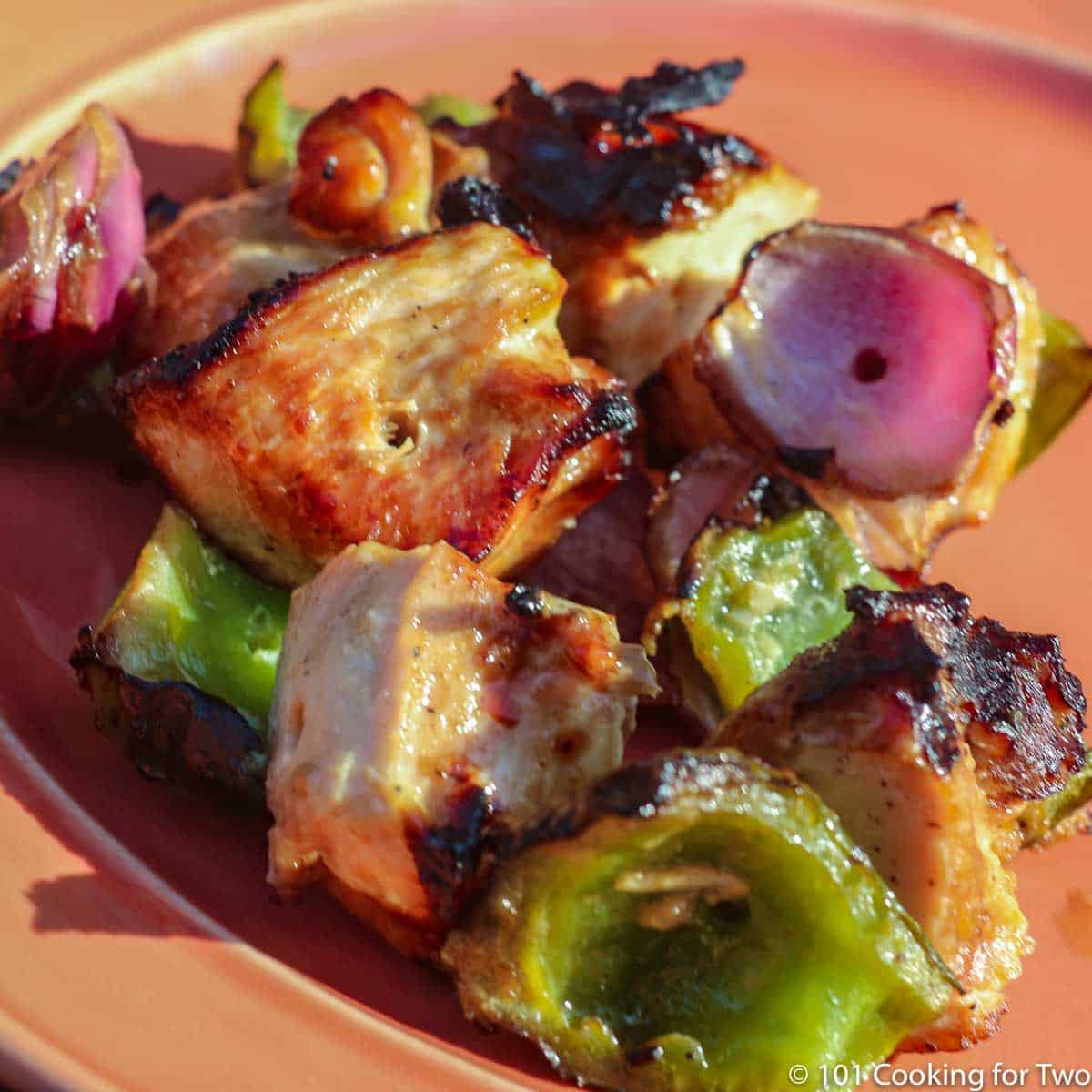grilled chicken chunks with veggies on orange plate.