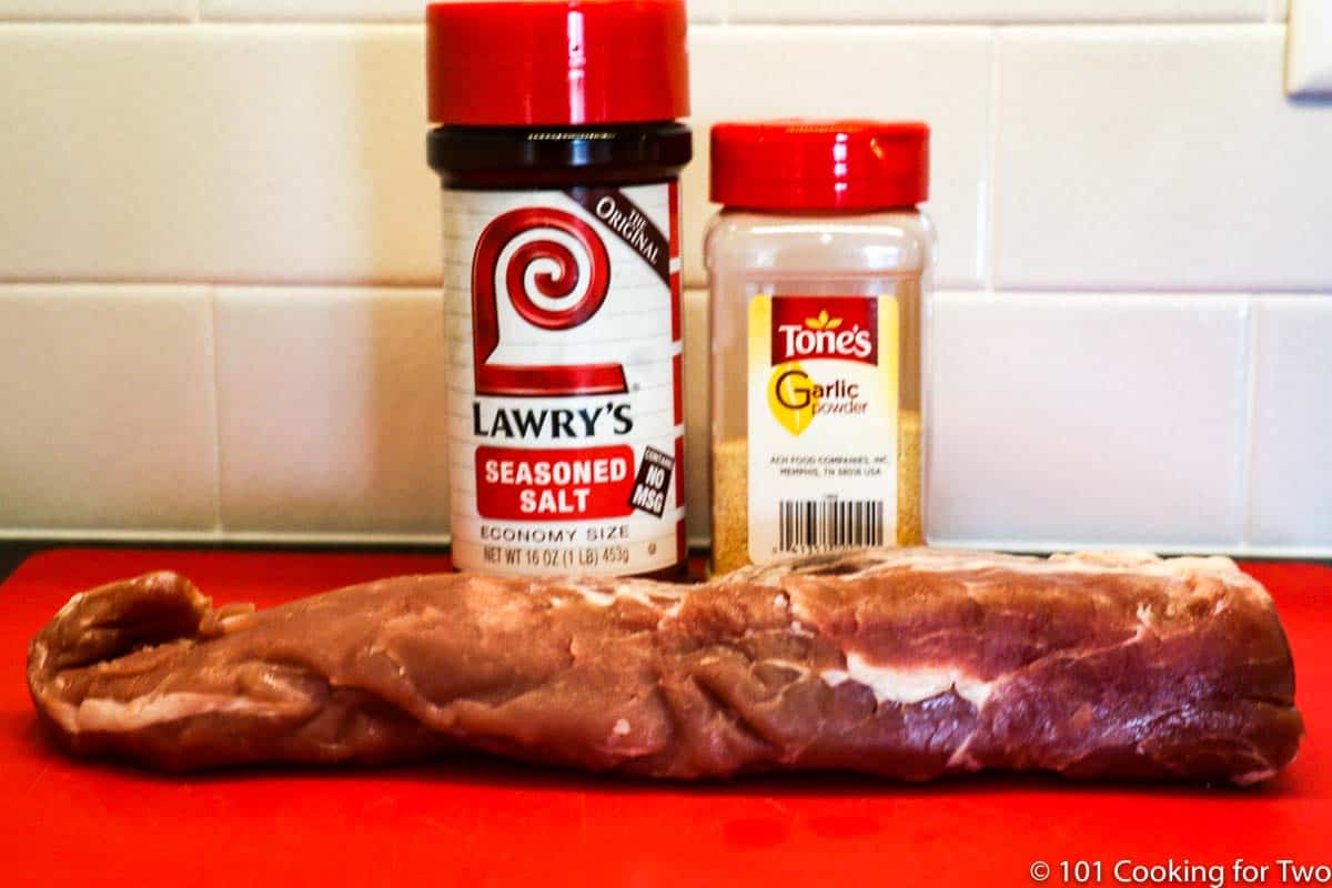 pork tenderloin with seaoning on red board.